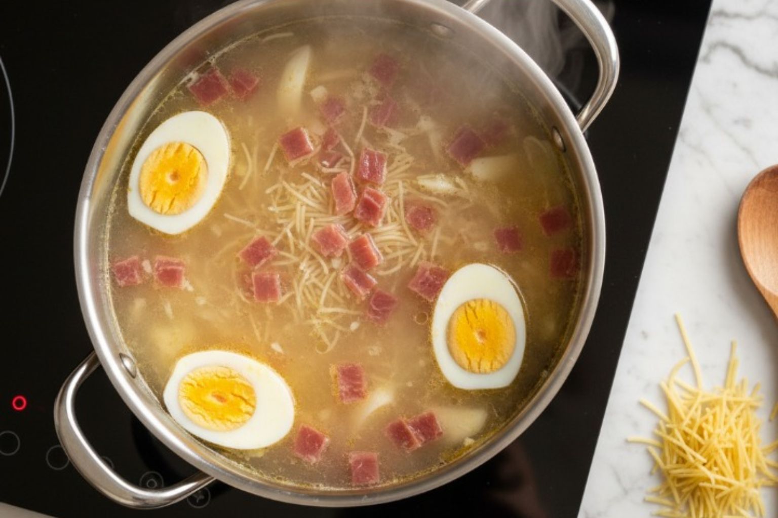Cocción de los Fideos, taquitos de jamon y huevo cocido en la Sopa de Picadillo Cociendo fideos finos tipo cabellín, jamon a taquitos y huevo cocido en el caldo caliente.