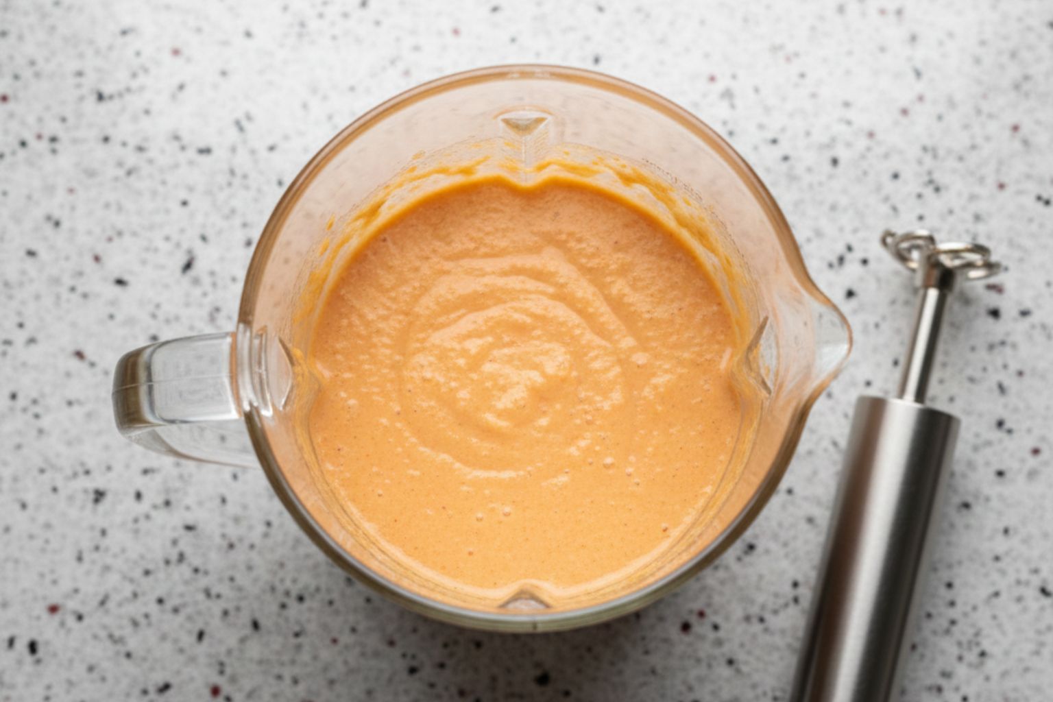 Vaso de batidora con la mezcla anaranjada y homogénea del pastel de pescado.